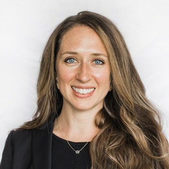 Rebecca Livengood is a white woman in her late thirties with long brown hair. She is wearing a black shirt and black blazer and is smiling.