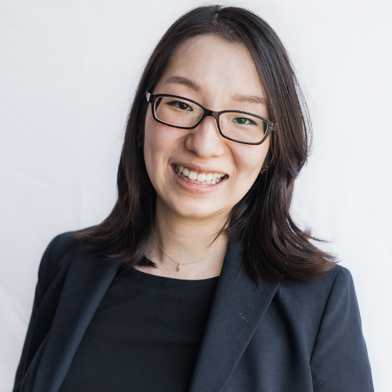 Soohyun Choi is a Korean woman in her 30s. She is wearing glasses and a dark suit and smiling.