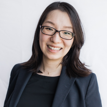 Soohyun Choi is a Korean woman in her 30s. She is wearing glasses and a dark suit and smiling.