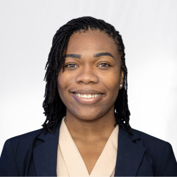 Ashley Brickhouse is a black woman in her mid-twenties with her hair styled in Sisterlocs. She is wearing a blush-colored top and black blazer and is smiling.